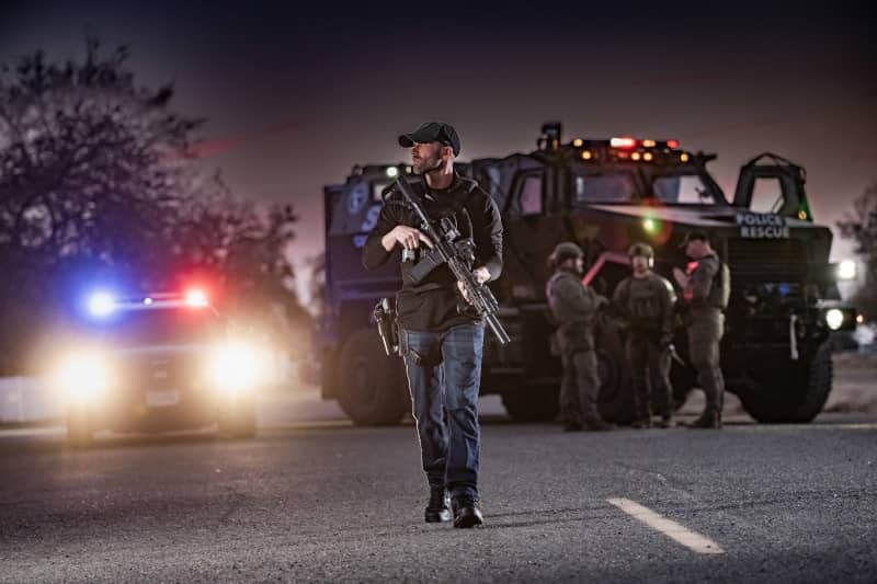 Cop walking on scene with long rifle