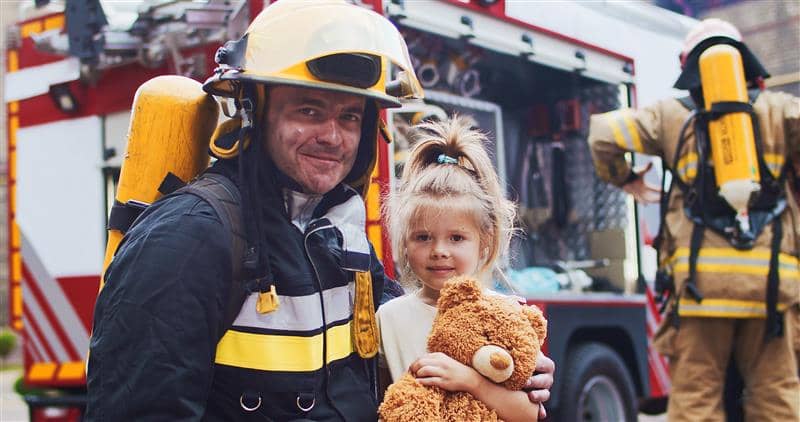 Fireman with young girl in front of fire truck