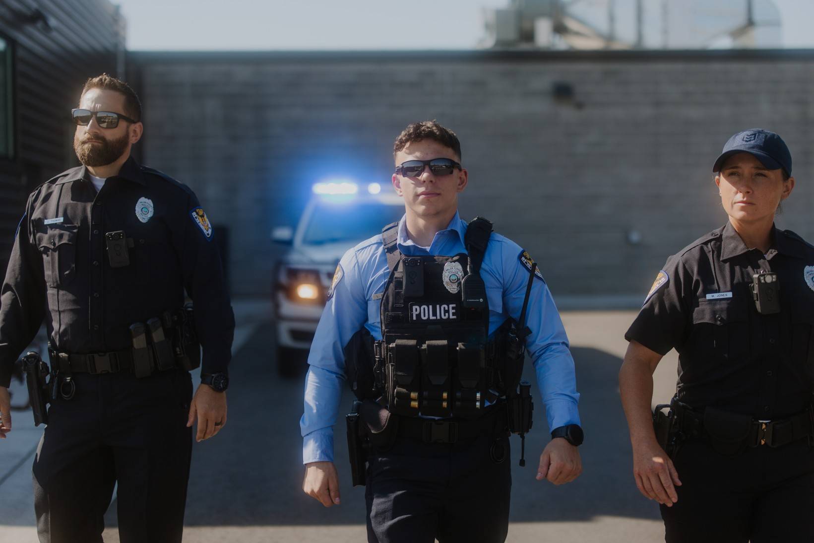 Police officers walking with car sirens in background